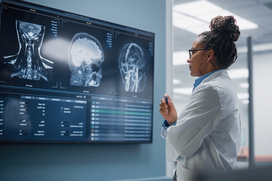 Confident Black Female Neurologist, Neuroscientist, Neurosurgeon, Looks at TV Screen with MRI Scan with Brain Images