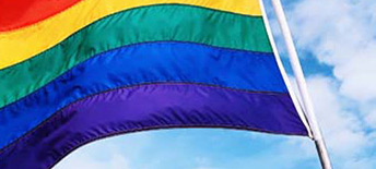 rainbow flag waving in the wind against blue sky