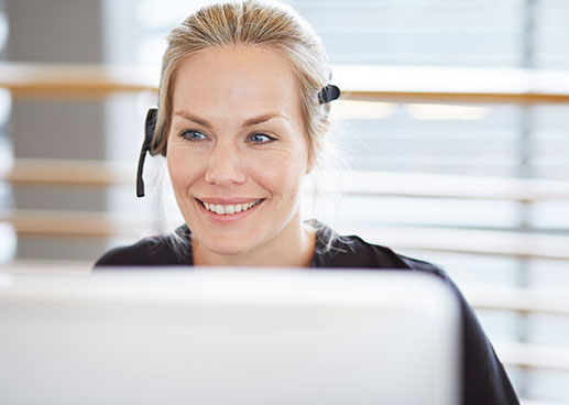 woman wearing headset taking a call in front of computer