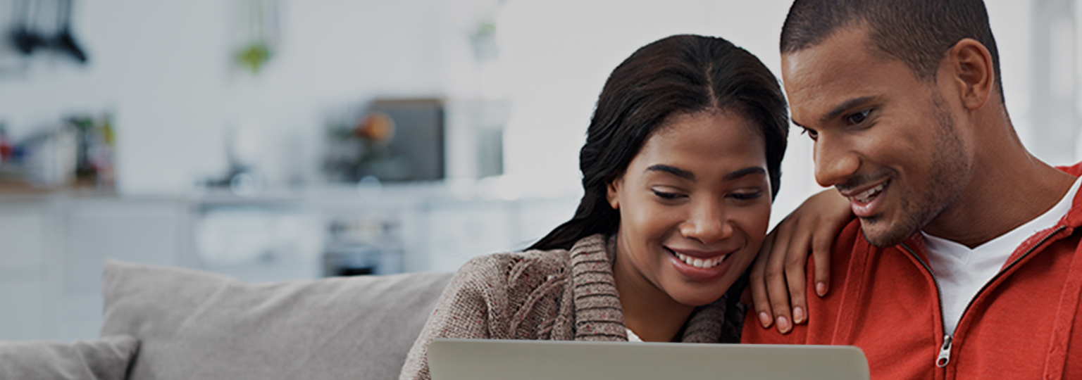 Couple sitting on the couch looking at laptop