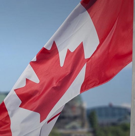 Canadian flag waving with Parliament Buildings hill and Library