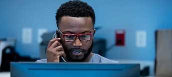 man on phone looking at laptop