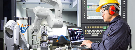 man wearing safety helmet, safety glasses and hearing protection headset and working with robot